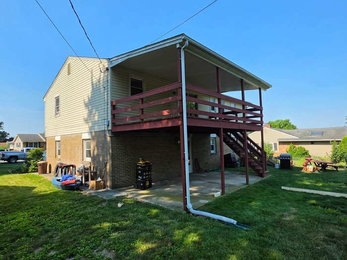 Original maroon-painted wood deck on the back of a two-story home before replacement — Central Pennsylvania