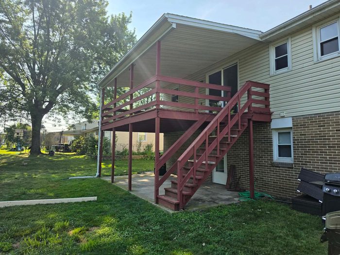 Weathered wood deck and stair run before demolition, with the porch roof above — Central Pennsylvania