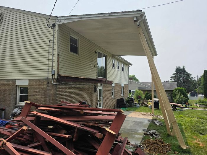 Old deck fully removed with the porch roof held on a temporary raking brace — Central Pennsylvania deck rebuild