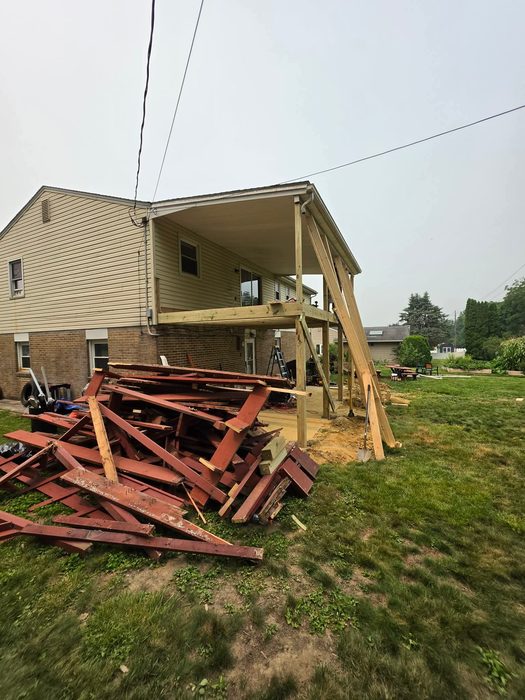 Pile of demolished maroon deck lumber beside the house during teardown — Central Pennsylvania