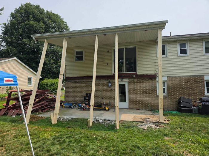 Porch roof standing on temporary shoring posts after the deck was stripped out — Central Pennsylvania