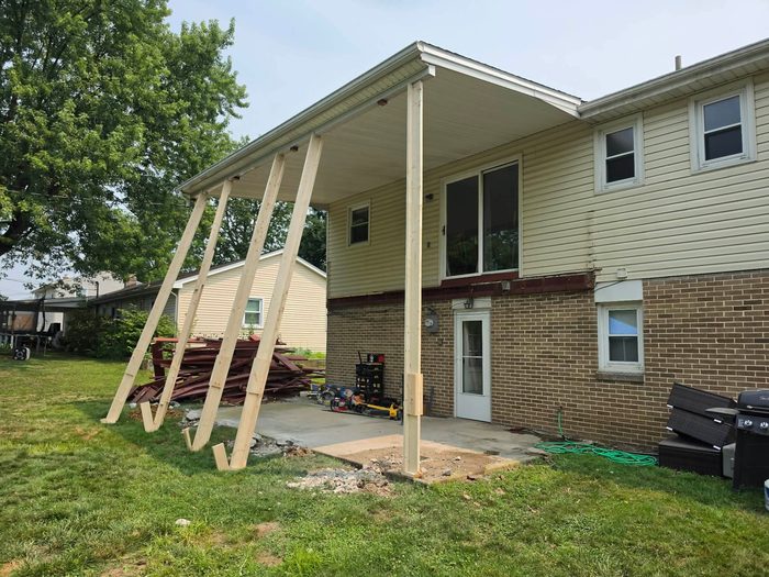 Temporary braces carrying the porch roof while the first new pressure-treated post is set — Central Pennsylvania