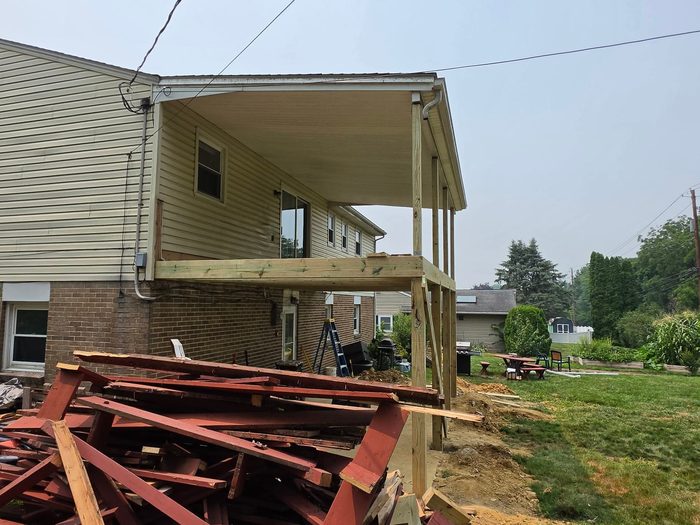 New pressure-treated beam set against the house at the start of the deck rebuild — Central Pennsylvania