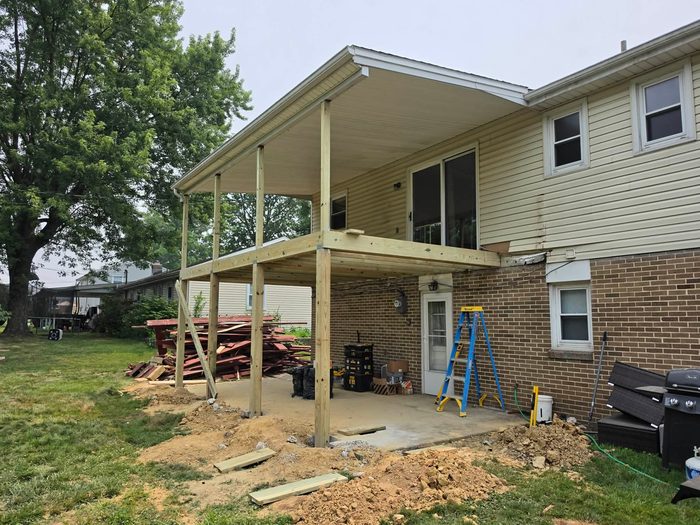 Pressure-treated posts on fresh footings with the porch roof re-supported — Central Pennsylvania deck rebuild