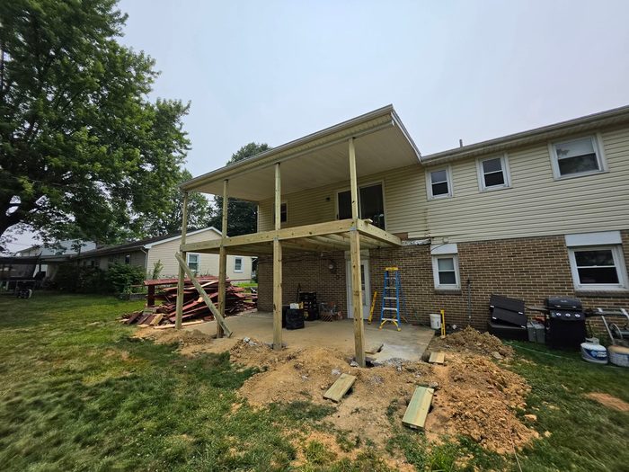 New deck framing viewed from the yard with fresh footings backfilled — Central Pennsylvania