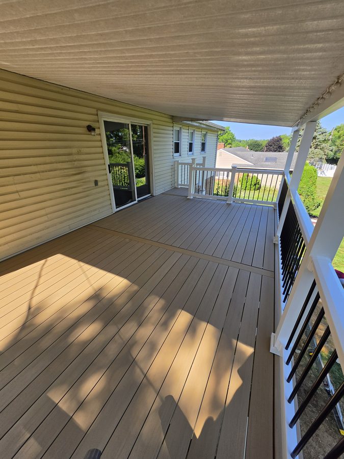 Covered deck looking toward the stair opening, with white vinyl railing and grey composite boards — Central Pennsylvania