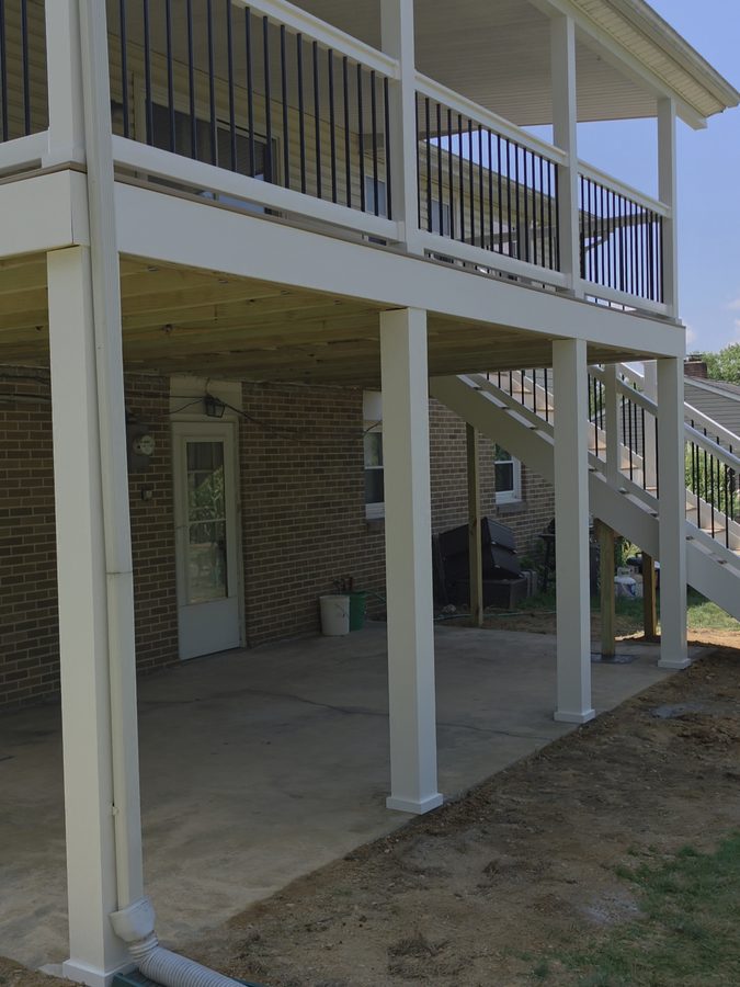 White-wrapped posts carrying the porch roof above the patio, viewed from beneath the finished deck — Central Pennsylvania