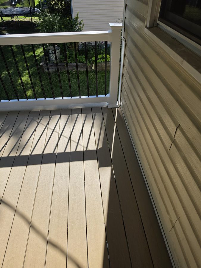 Composite deck boards and picture-frame border meeting the white vinyl railing — Central Pennsylvania